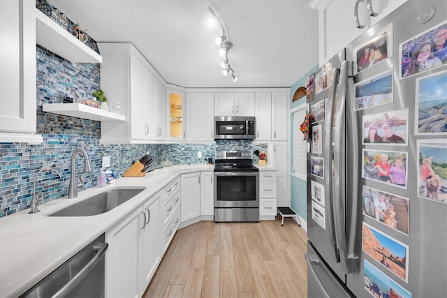 kitchen featuring light hardwood / wood-style floors, stainless steel appliances, sink, backsplash, and white cabinetry