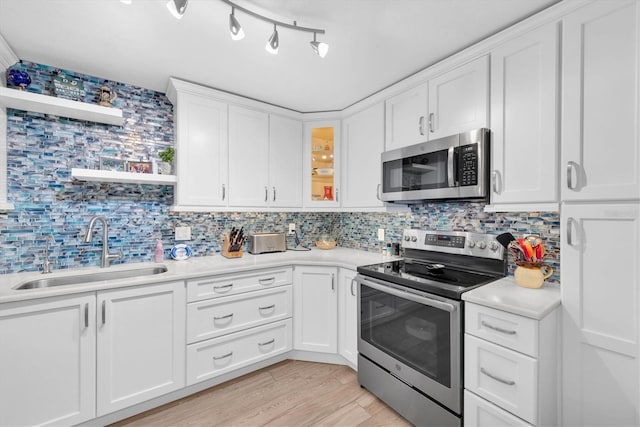 kitchen with white cabinetry, appliances with stainless steel finishes, backsplash, sink, and light hardwood / wood-style flooring