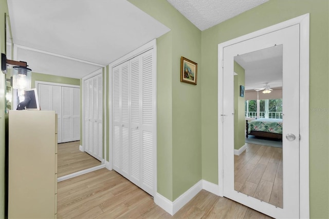 hall with light wood-type flooring and a textured ceiling