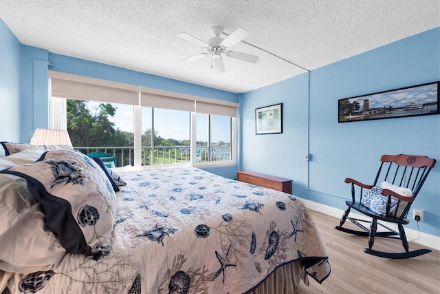 bedroom with light hardwood / wood-style floors, ceiling fan, and a textured ceiling