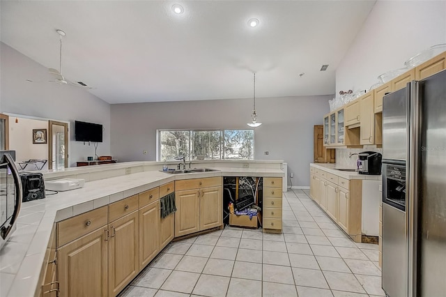 kitchen featuring sink, stainless steel refrigerator with ice dispenser, vaulted ceiling, and light tile patterned floors