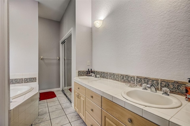 bathroom with tiled bath, tile patterned flooring, and vanity