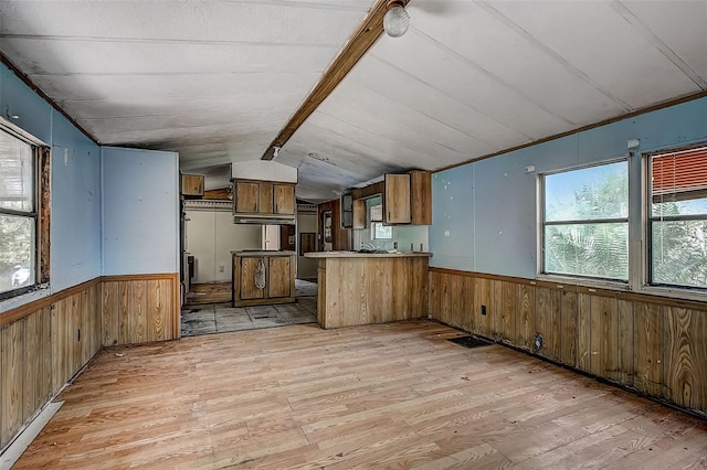 kitchen with vaulted ceiling, wooden walls, light hardwood / wood-style flooring, and kitchen peninsula