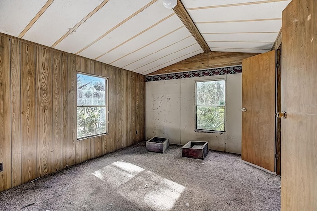 unfurnished room featuring wood walls, light carpet, and vaulted ceiling