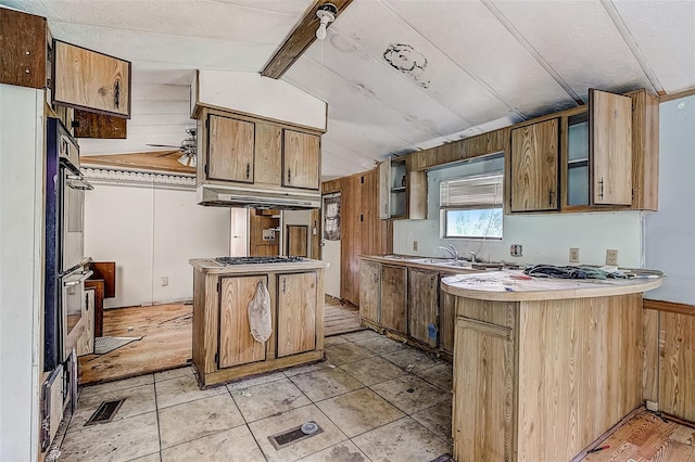 kitchen featuring wood walls, sink, kitchen peninsula, lofted ceiling, and ceiling fan