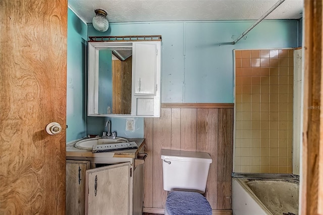 bathroom featuring wood walls, toilet, and vanity