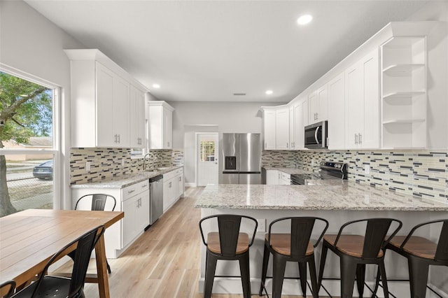 kitchen featuring stainless steel appliances, white cabinets, light hardwood / wood-style flooring, and kitchen peninsula