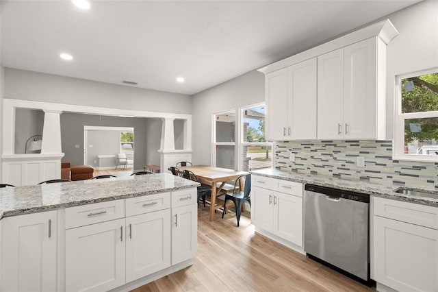 kitchen featuring stainless steel dishwasher, a wealth of natural light, and white cabinets