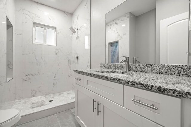 bathroom with tiled shower, vanity, tile patterned floors, and toilet