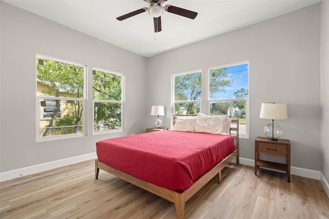 bedroom featuring ceiling fan, multiple windows, and light hardwood / wood-style floors