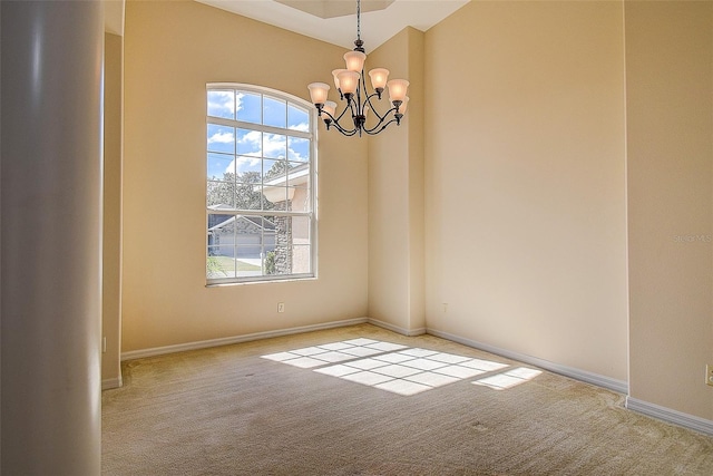 spare room featuring light carpet and an inviting chandelier