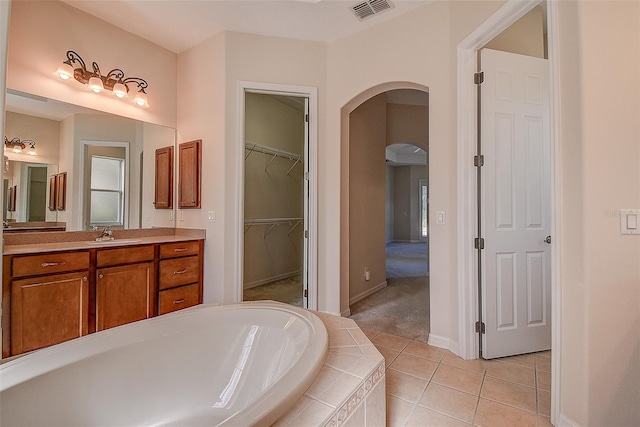 bathroom with vanity, tile patterned flooring, and a relaxing tiled tub