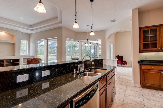 kitchen featuring sink, dark stone countertops, a textured ceiling, decorative light fixtures, and dishwasher