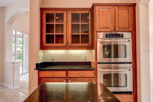 kitchen featuring dark stone counters, light tile patterned flooring, and double oven