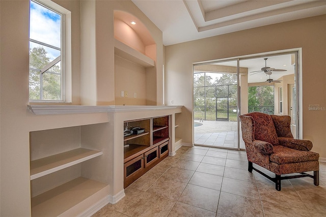 living area featuring a wealth of natural light, ceiling fan, built in features, and light tile patterned flooring