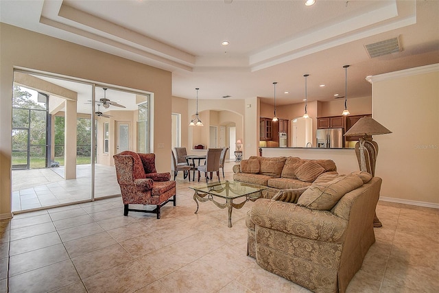 living room with light tile patterned floors, ceiling fan, and a raised ceiling