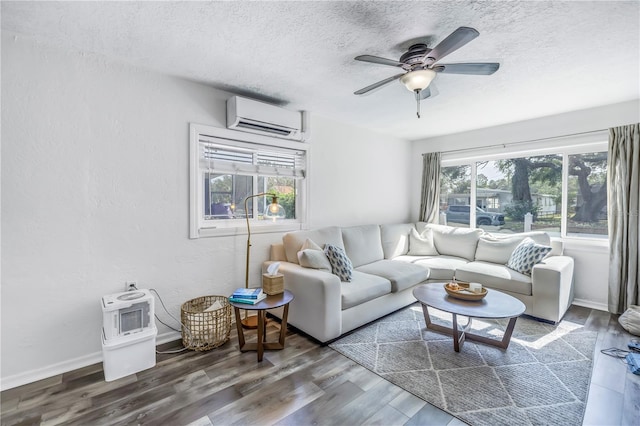 living room with dark wood-type flooring, a wall unit AC, ceiling fan, and plenty of natural light