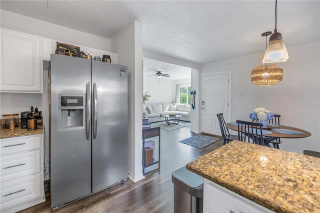 kitchen with white cabinetry, ceiling fan, hanging light fixtures, dark wood-type flooring, and stainless steel fridge