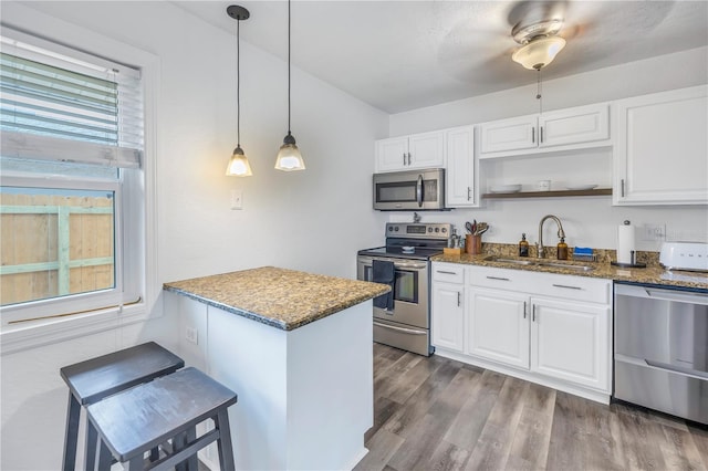 kitchen featuring white cabinetry, sink, appliances with stainless steel finishes, hanging light fixtures, and dark hardwood / wood-style flooring