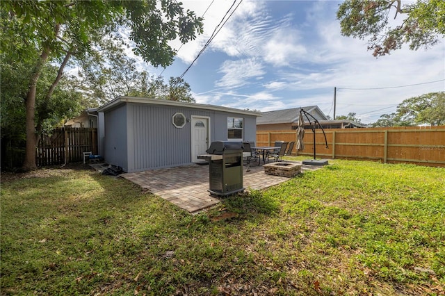 back of property featuring a fire pit, a lawn, and a patio area