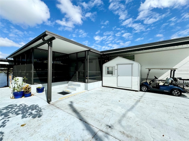 rear view of property featuring a shed and a sunroom