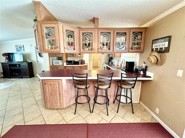 kitchen featuring a textured ceiling, kitchen peninsula, sink, and crown molding