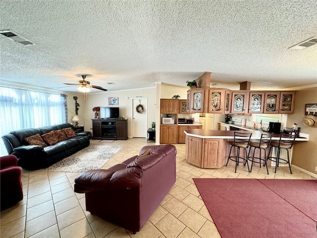 living room featuring ornamental molding, a textured ceiling, light tile patterned floors, and ceiling fan