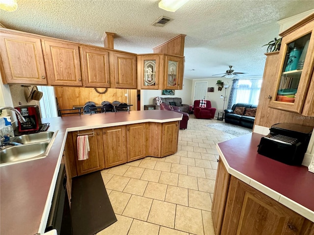 kitchen with light tile patterned flooring, a textured ceiling, sink, kitchen peninsula, and ceiling fan