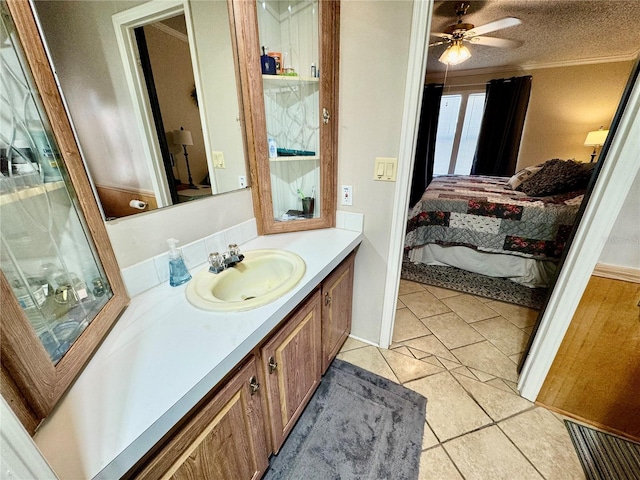 bathroom with ornamental molding, vanity, a textured ceiling, tile patterned flooring, and ceiling fan