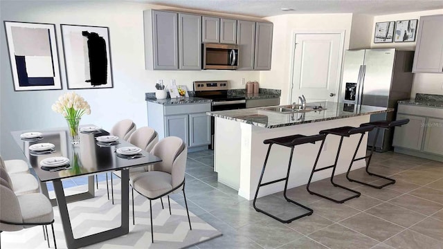 kitchen featuring sink, appliances with stainless steel finishes, a breakfast bar area, light tile patterned floors, and an island with sink