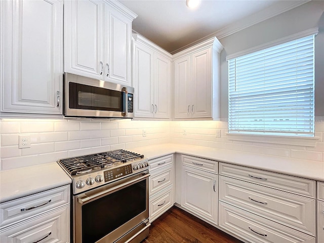 kitchen with backsplash, dark hardwood / wood-style flooring, white cabinets, and appliances with stainless steel finishes