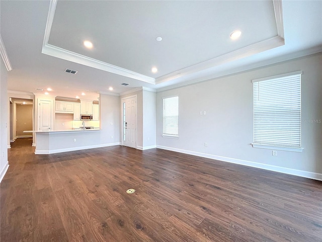 unfurnished living room featuring a raised ceiling and dark wood-type flooring