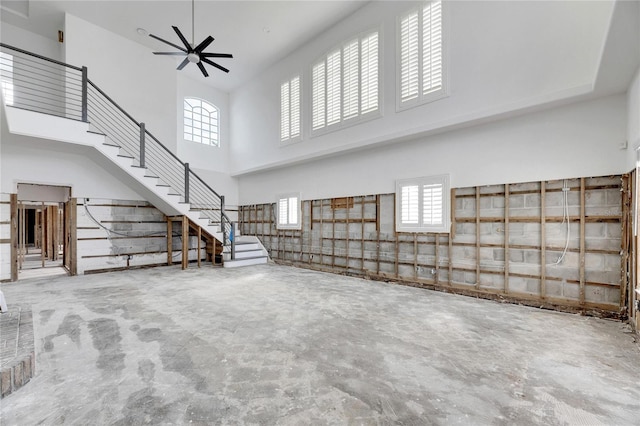 unfurnished living room featuring a high ceiling, ceiling fan, and concrete flooring