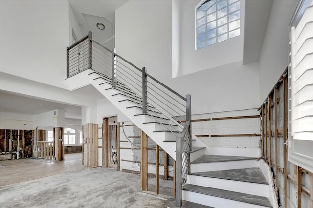 stairway featuring a towering ceiling and concrete flooring