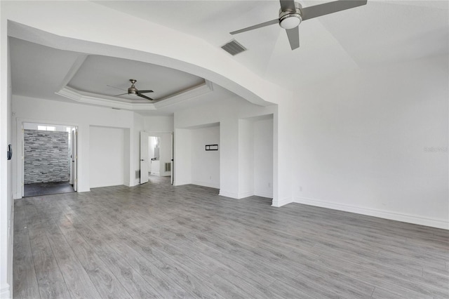 unfurnished living room with wood-type flooring, ceiling fan, and a raised ceiling