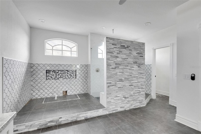 bathroom featuring tile patterned floors, tiled shower, and tile walls