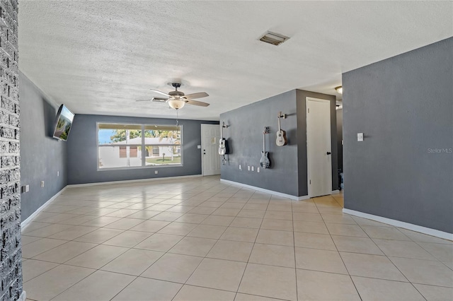 empty room featuring light tile patterned floors, a textured ceiling, and ceiling fan