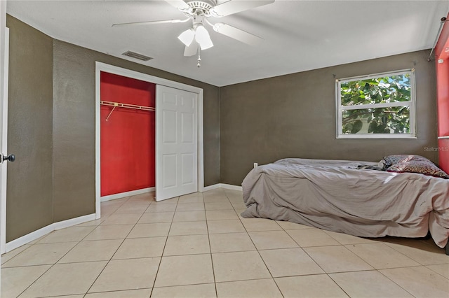 bedroom with ceiling fan, light tile patterned flooring, and a closet