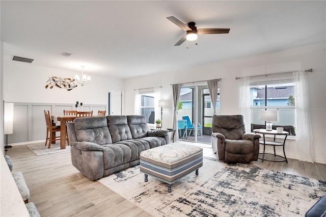 living room with light hardwood / wood-style floors and ceiling fan with notable chandelier