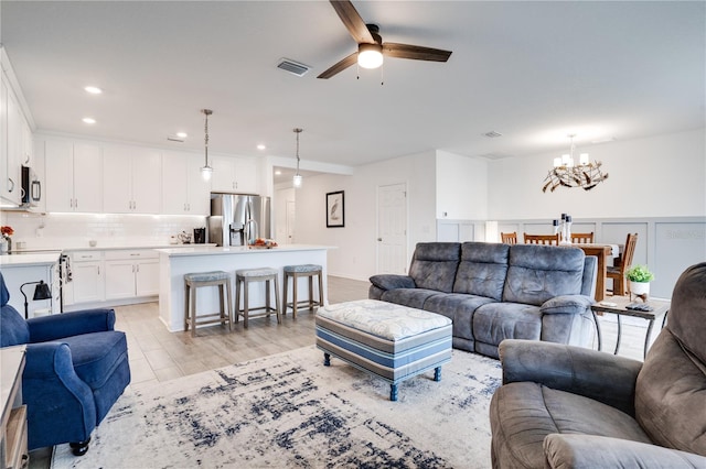 living room featuring light hardwood / wood-style floors and ceiling fan with notable chandelier