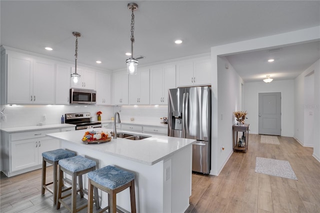 kitchen featuring an island with sink, sink, light hardwood / wood-style flooring, and appliances with stainless steel finishes