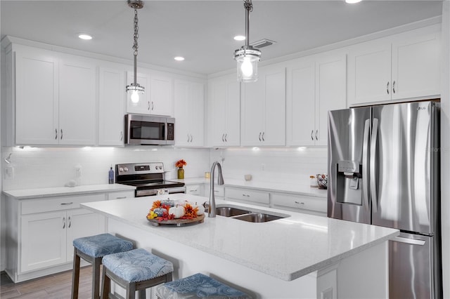 kitchen with stainless steel appliances, sink, a breakfast bar area, hanging light fixtures, and light hardwood / wood-style flooring