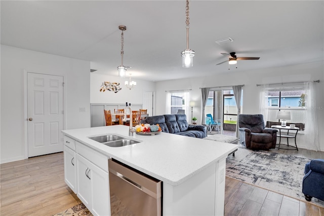 kitchen featuring light wood-type flooring, hanging light fixtures, a kitchen island with sink, and dishwasher