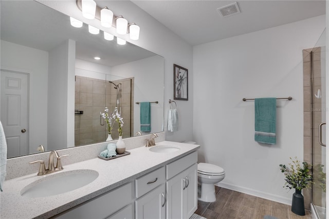 bathroom featuring hardwood / wood-style flooring, a shower with door, vanity, and toilet