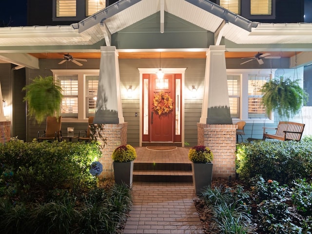 doorway to property featuring ceiling fan, a porch, and brick siding