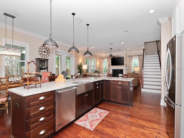 kitchen featuring dark brown cabinetry, stainless steel appliances, a sink, visible vents, and open floor plan