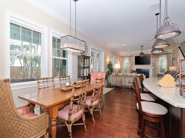 dining room with ornamental molding, dark wood-type flooring, a fireplace, and ceiling fan