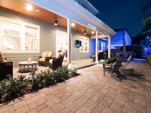 patio at night with fence and a ceiling fan