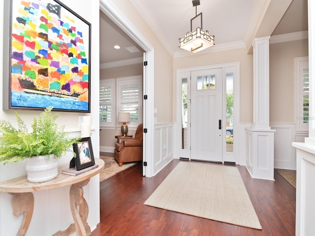 entryway with ornamental molding, a wainscoted wall, dark wood-type flooring, and decorative columns