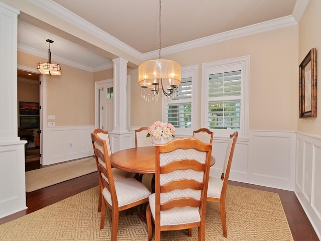 dining space with ornate columns, a chandelier, dark wood-type flooring, and a wainscoted wall